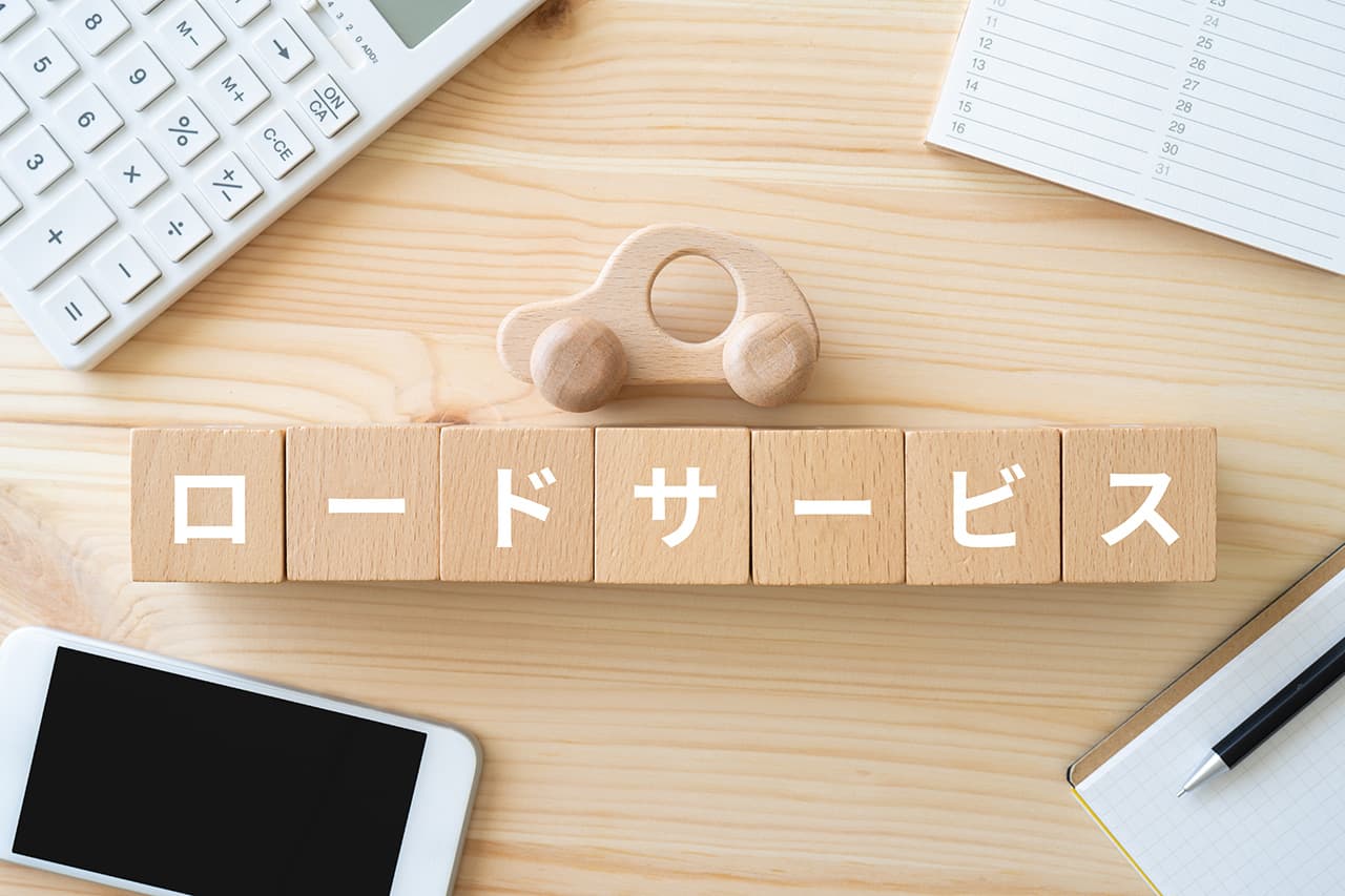 ロードサービスと書かれたブロック、電卓、スマホ、ノート、おもちゃの車